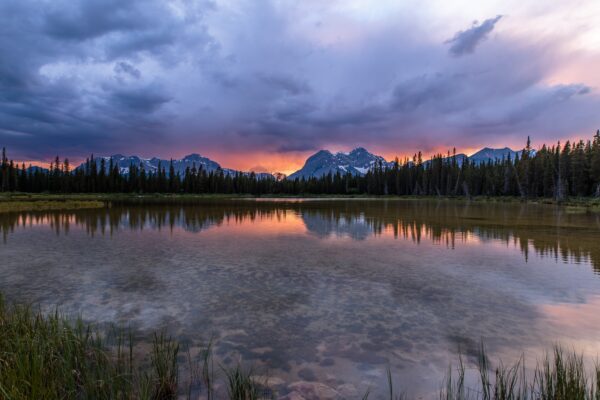 The sun sets over a pond in Spray Valley Provincal Park in Alberta, Canada.